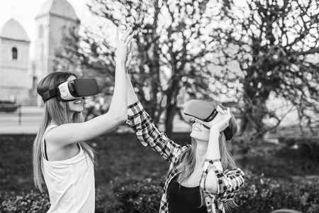 Two young girls enjoy virtual reality glasses outdoor, black and whiteの写真素材