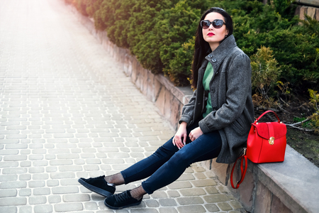 Young brunette girl sitting outdoor with red backpackの写真素材