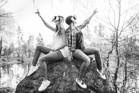 Two young girls enjoy virtual reality glasses outdoor, black and whiteの写真素材
