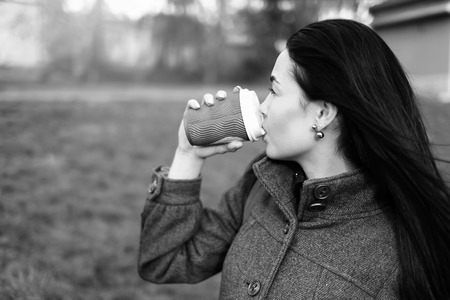 Long hair brunette girl with cup of coffee outdoor, black and whiteの写真素材