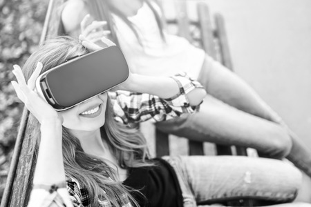 Two young girls enjoy virtual reality glasses outdoor, black and whiteの写真素材