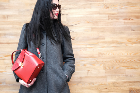 Long hair brunette girl near wooden wall with red backpackの写真素材