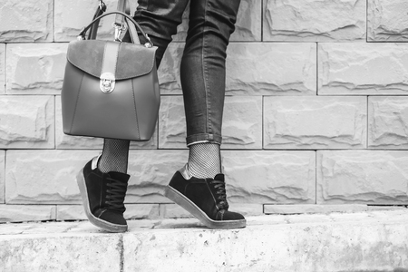 Women's feet near wall with red backpack in hands, black and whiteの写真素材