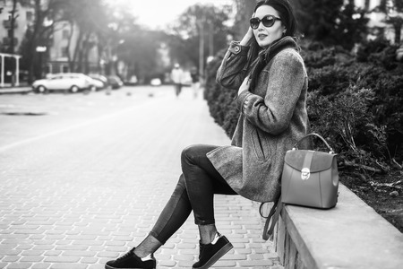 Young brunette girl sitting outdoor with red backpack, black and whiteの写真素材