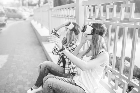 Two young girls enjoy virtual reality glasses outdoor, black and whiteの写真素材
