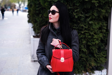 Woman on the street with red backpack in handsの写真素材