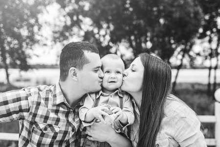 Young happy parents playing with little son outdoor in the park, black and whiteの写真素材