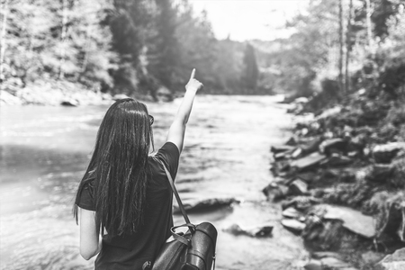 Tourist girl enjoy nature near mountain river, black and whiteの写真素材
