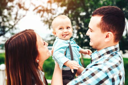 Young happy parents playing with little son outdoor in the parkの写真素材