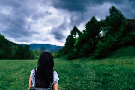 Woman with backpack in the mountains with cloudy skyの写真素材