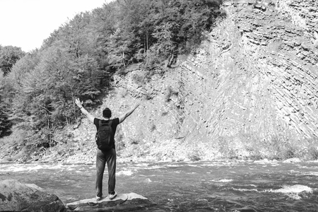 Traveler with backpack relaxing near mountain river, black and whiteの写真素材