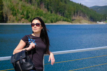 Yong brunette girl relaxing near mountain lakeの写真素材