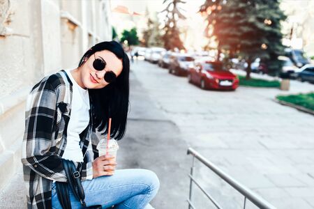 Pretty brunette girl enjoy cold coffee on the streetの写真素材