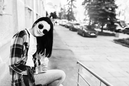 Pretty brunette girl enjoy cold coffee on the street, black and white