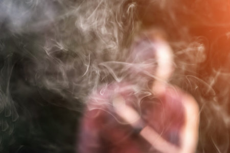 Man smoking electronic cigarette outdoor, focus on steam