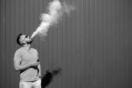 Vaper smoke electronic cigarette outdoor near wallの写真素材