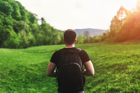 Young tourist man in the mountains with sky and forest on backgroundの写真素材