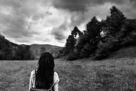 Woman with backpack in the mountains with cloudy sky, black and whiteの写真素材