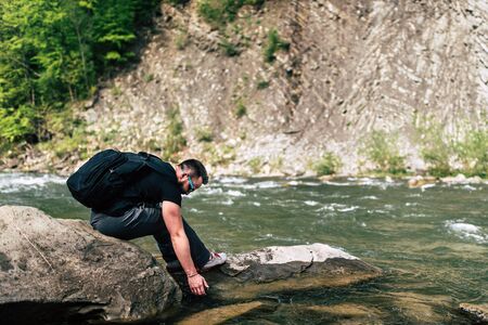 Traveler with backpack relaxing near mountain riverの写真素材