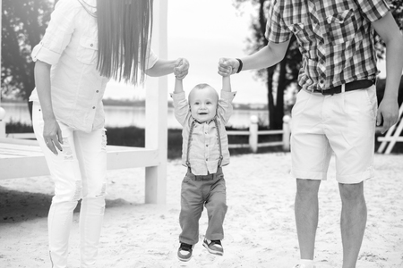 Young happy parents playing with little son outdoor in the park, black and whiteの写真素材