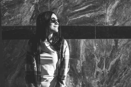 Cute brunette girl standing near stone wall outdoor, black and whiteの写真素材