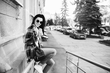 Pretty brunette girl enjoy cold coffee on the street, black and whiteの写真素材