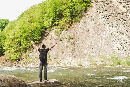 Traveler with backpack relaxing near mountain riverの写真素材