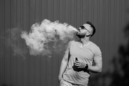 Man smoking electronic sigarette outdoor, black and whiteの写真素材