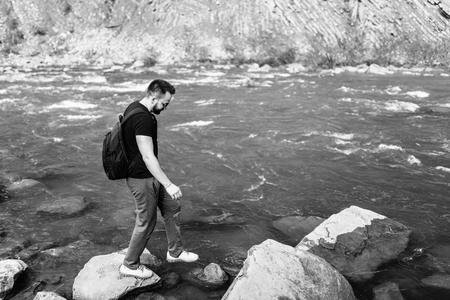 Traveler with backpack relaxing near mountain river, black and whiteの写真素材