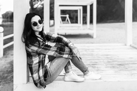 Cute brunette girl relaxing on the wooden bench outdoor, black and whiteの写真素材
