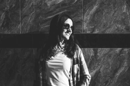 Cute brunette girl standing near stone wall outdoor, black and whiteの写真素材