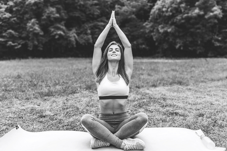 Pretty sporty girl showing stretching exercises outdoor, black and whiteの写真素材