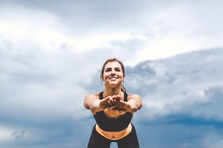 Pretty sporty girl showing stretching exercises outdoorの写真素材