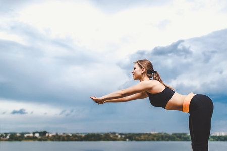 Pretty sporty girl showing stretching exercises outdoorの写真素材