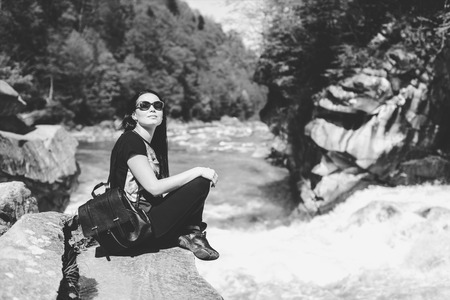 Tourist girl enjoy nature near mountain river, black and whiteの写真素材
