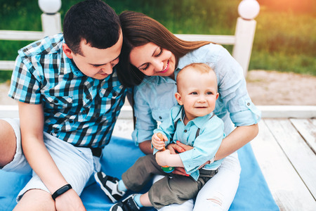 Young happy parents playing with little son outdoor in the parkの写真素材