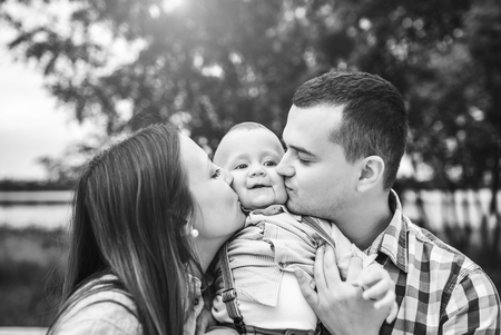Young happy parents playing with little son outdoor in the park, black and whiteの写真素材