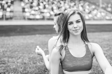 Two pretty sporty girls relaxing after workout outdoor, black and whiteの写真素材