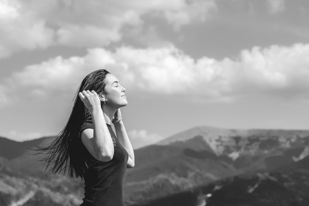 Long hair brunette girl on the top of the mountain enjoying fresh airの写真素材