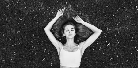 Cute long hair girl relaxing on the grass outdoor, black and whiteの写真素材