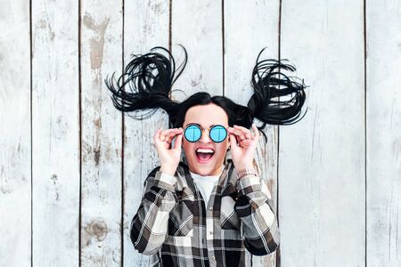 Young happy brunette girl lying on wooden backroundの写真素材