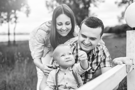 Young happy parents playing with little son outdoor in the park, black and whiteの写真素材