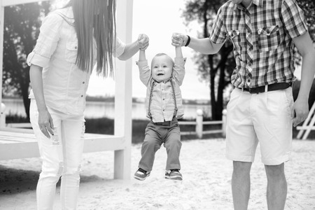 Young happy parents playing with little son outdoor in the park, black and whiteの写真素材
