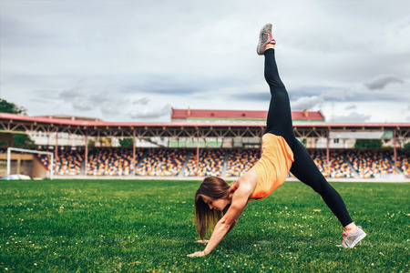 Pretty sporty girl showing stretching exercises outdoorの写真素材