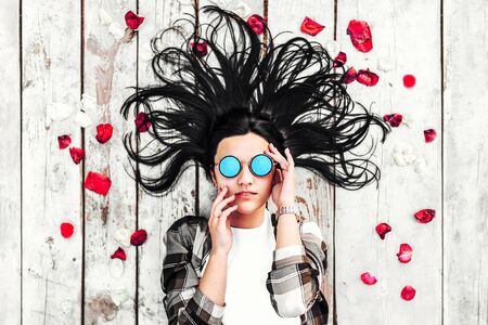 Young happy girl lying on wooden backround with tulip petalsの写真素材