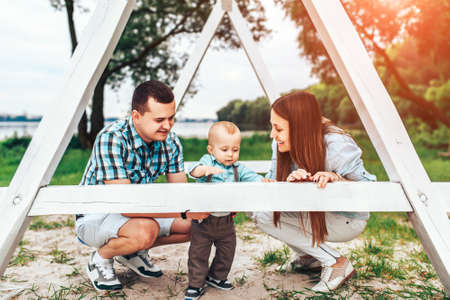 Young happy parents playing with little son outdoor in the parkの写真素材