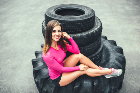 Sporty girl near huge old tires outdoorの写真素材