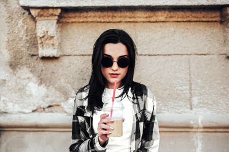Pretty brunette girl drinking cold coffee outdoorの写真素材