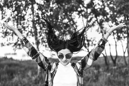 Happy pretty girl outdoor showing tongue and throw her hair, black and whiteの写真素材