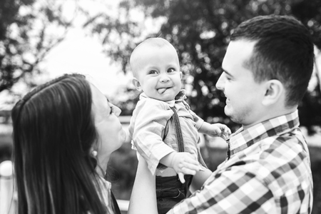 Young happy parents playing with little son outdoor in the park, black and whiteの写真素材